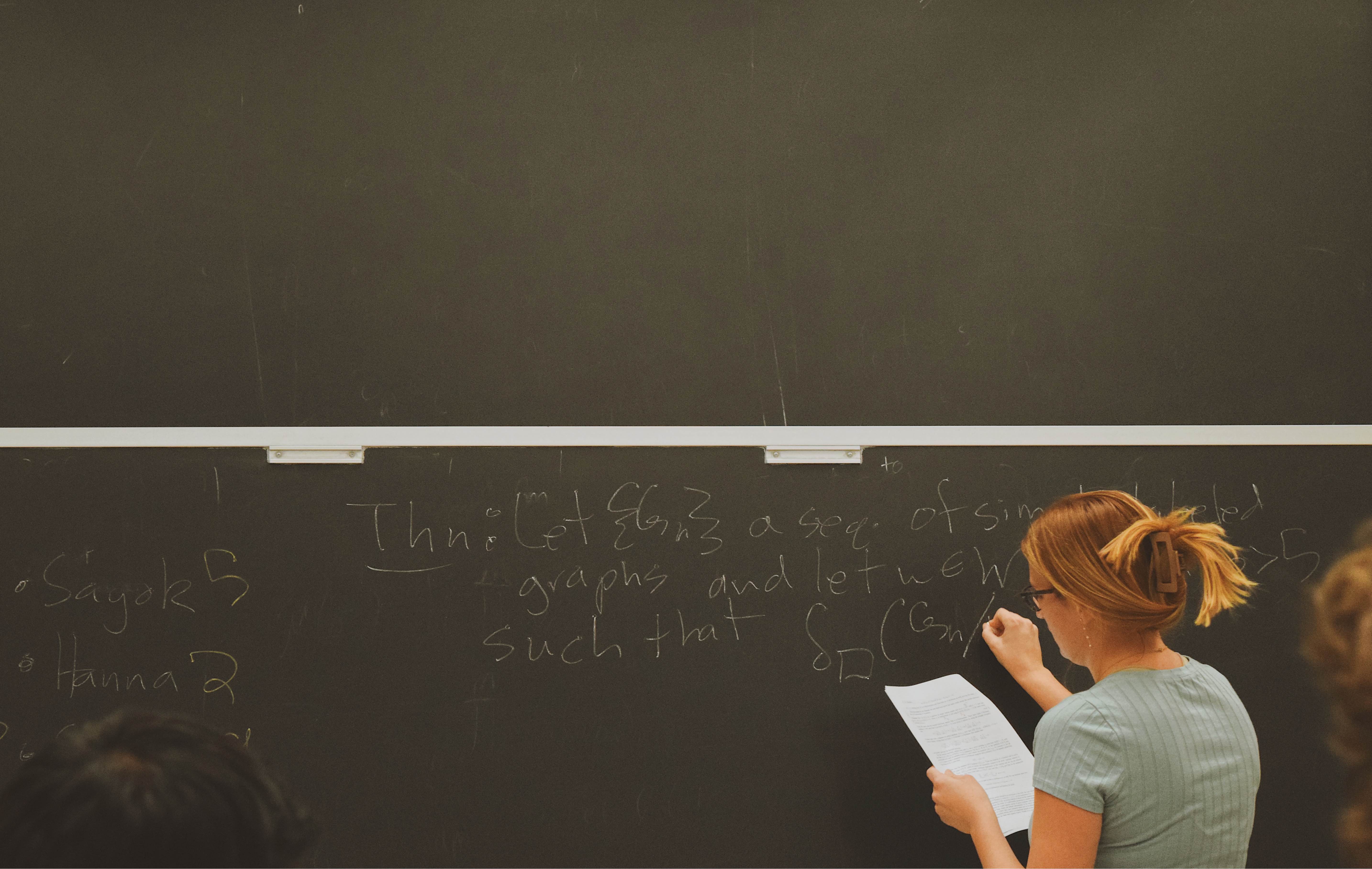 Emily writing mathematics on a chalkboard